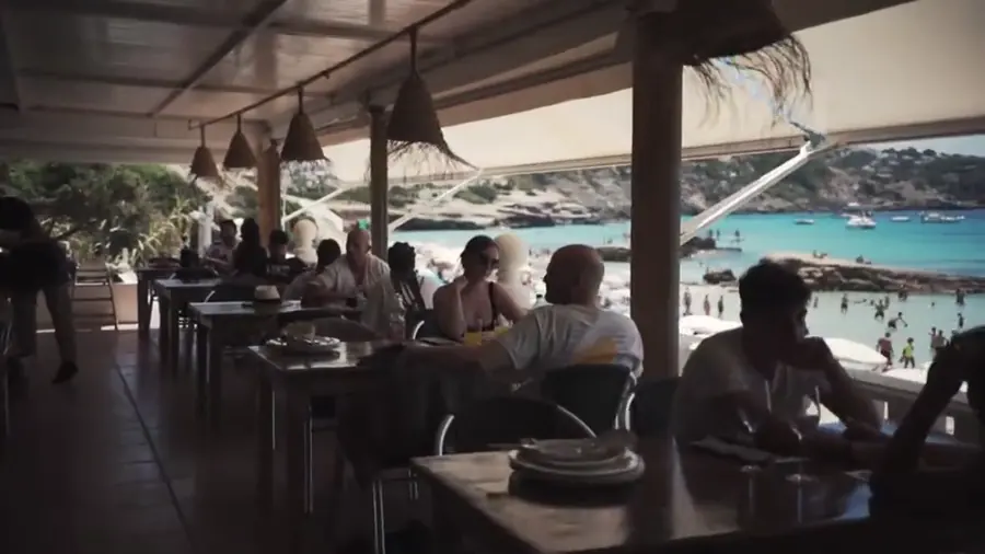 Terraza de un restaurante de playa en Ibiza con clientes a mediodía